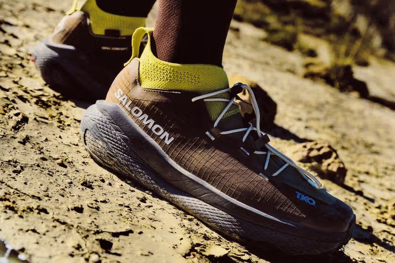 Salomon x Pas Normal Studios GRVL Concept hybrid training shoe with PEBA supercritical foam midsole and carbon blade construction, displayed with RACE SKIN 2 running vest from the T.K.O. SS26 collection