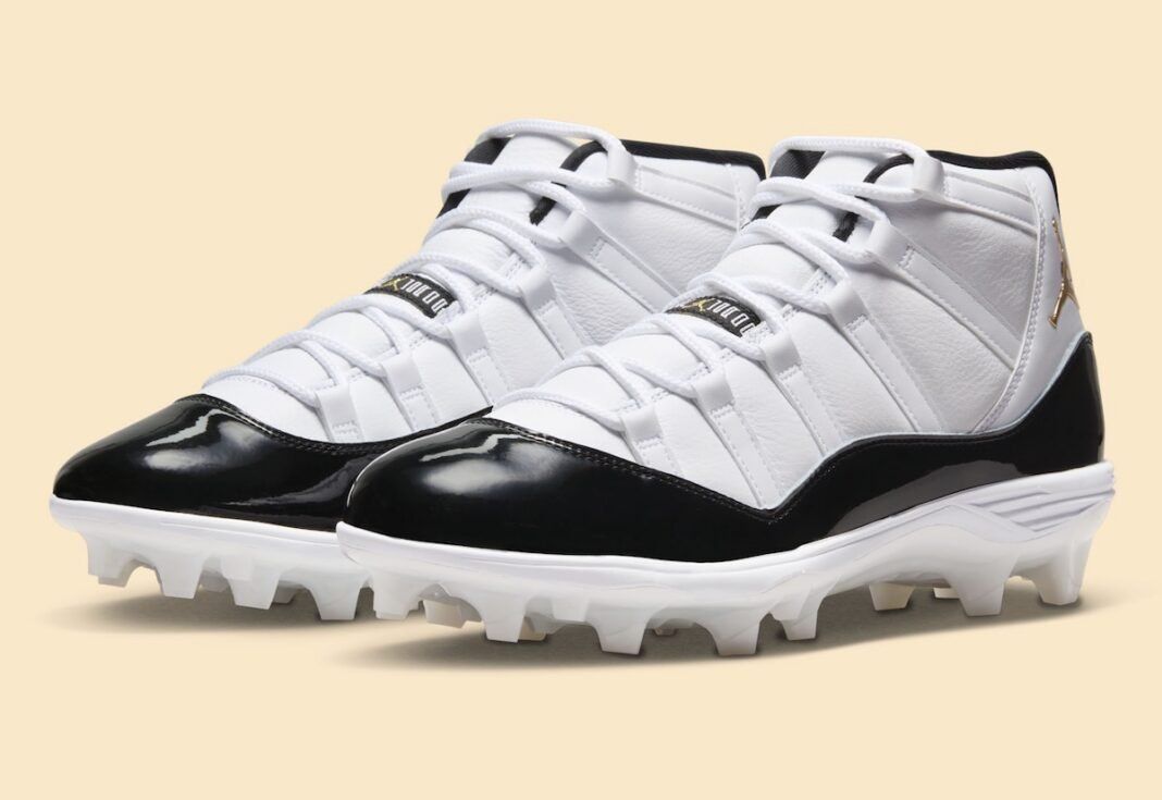 Air Jordan 11 MCS Cleat DMP in white leather with black patent mudguard and metallic gold details, shown with off-white cleated outsole for baseball performance