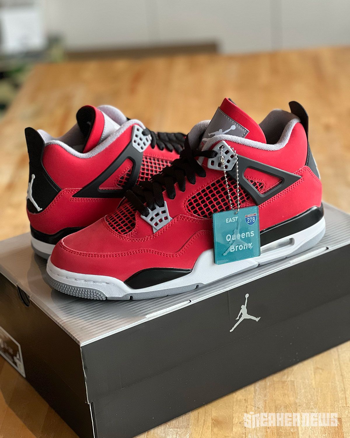 Air Jordan 4 "Toro Bravo" in red and black, shown from multiple angles alongside collectible hangtag featuring 278 Interstate and NYC borough graphics