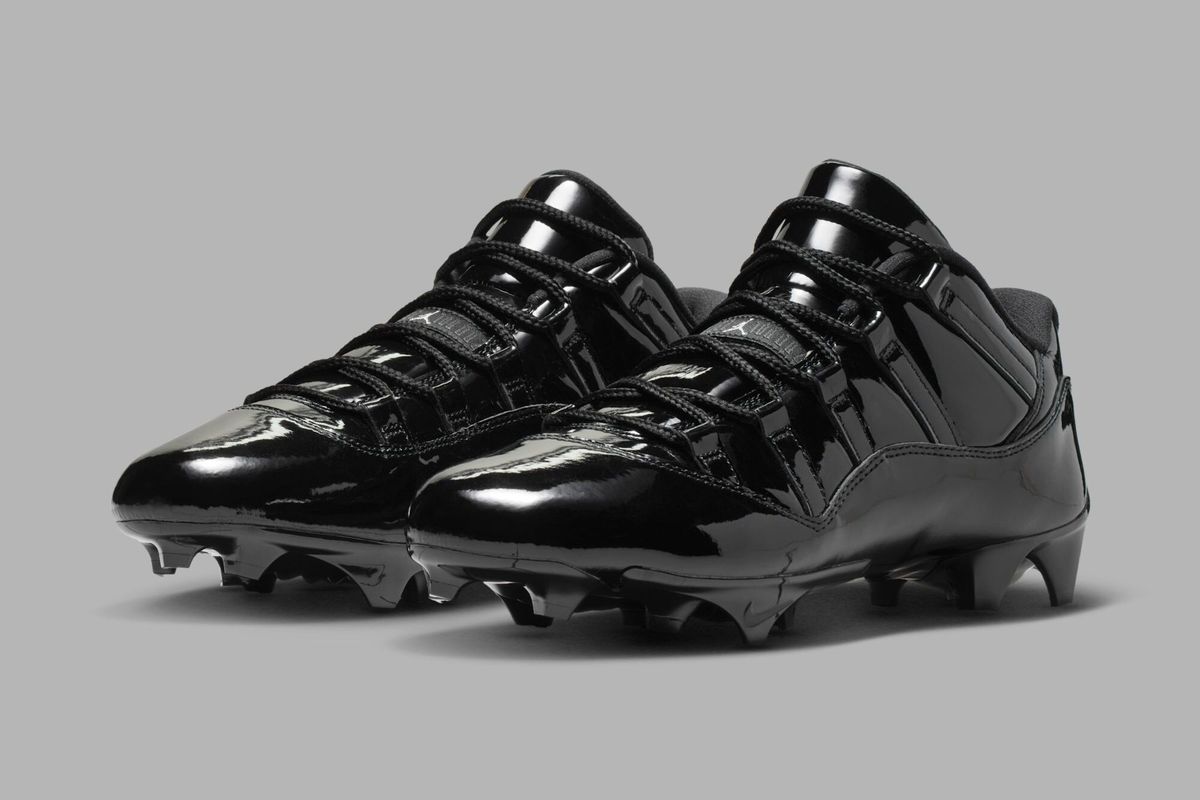 Air Jordan 11 TD Low Patent Leather Football Cleat in black, shown from the side profile highlighting the patent leather construction and low-cut design