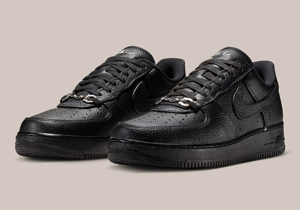 Nike Air Force 1 Low in black pebbled leather featuring silver loafer buckle accent at lace collar