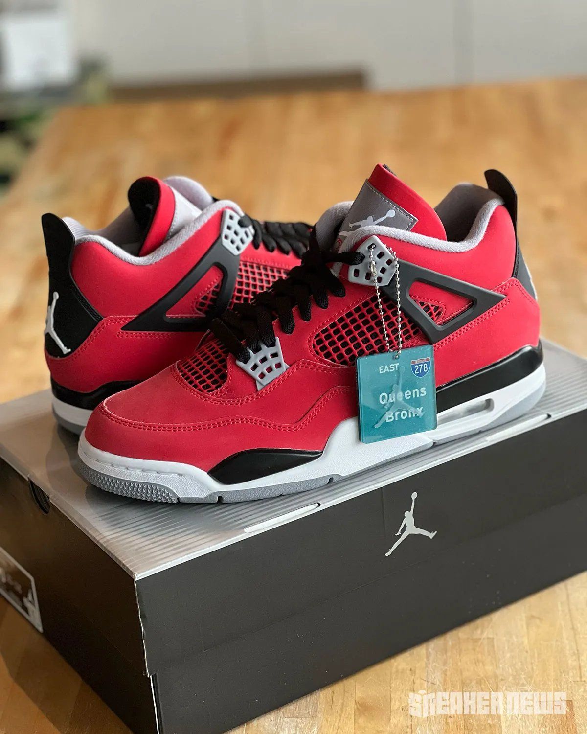 Air Jordan 4 "Toro Bravo" in red and black, shown from multiple angles alongside collectible hangtag featuring 278 Interstate and NYC borough graphics