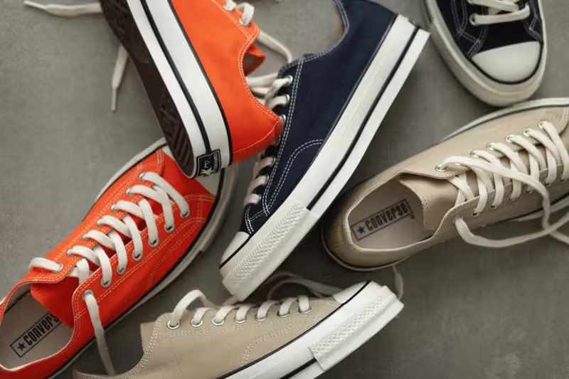 Three colorways of the Converse All Star Lgcy Ox—Orange, Dark Navy, and Sand—displayed with tonal canvas uppers and aged finishes