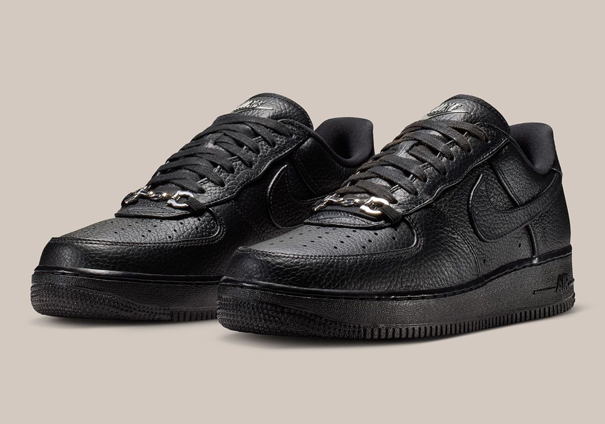 Nike Air Force 1 Low in black pebbled leather featuring silver loafer buckle accent at lace collar