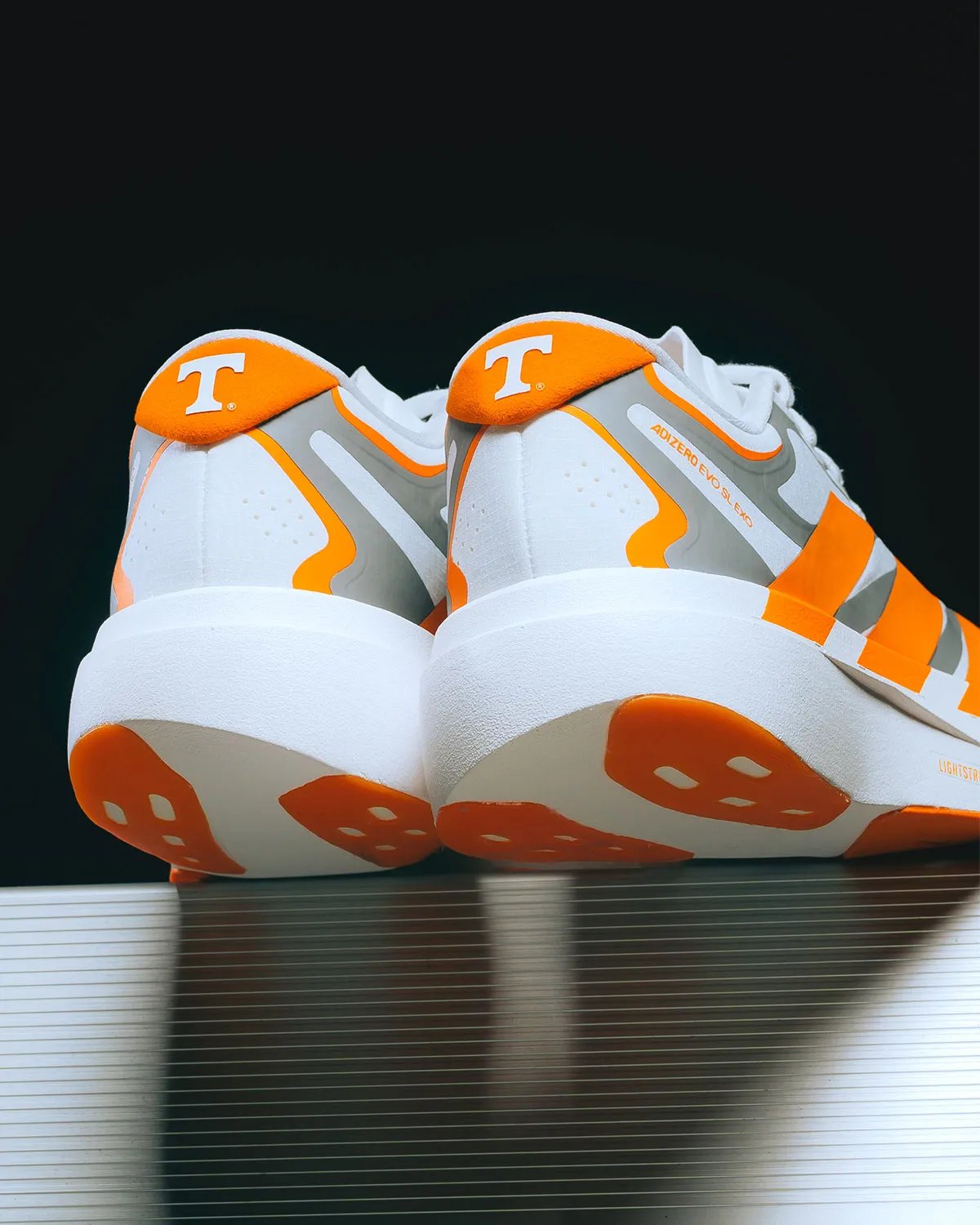adidas EVO SL EXO in Tennessee colorway featuring white base, metallic silver exoskeleton, and orange Three Stripes with Volunteers branding - detail view 5