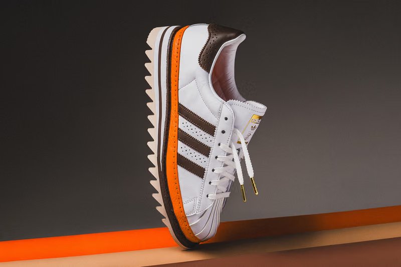 adidas Originals x CLOT Superstar "Unity Orange" sneaker featuring vibrant orange leather upper with white Three Stripes and gold lace tips - detail view 4