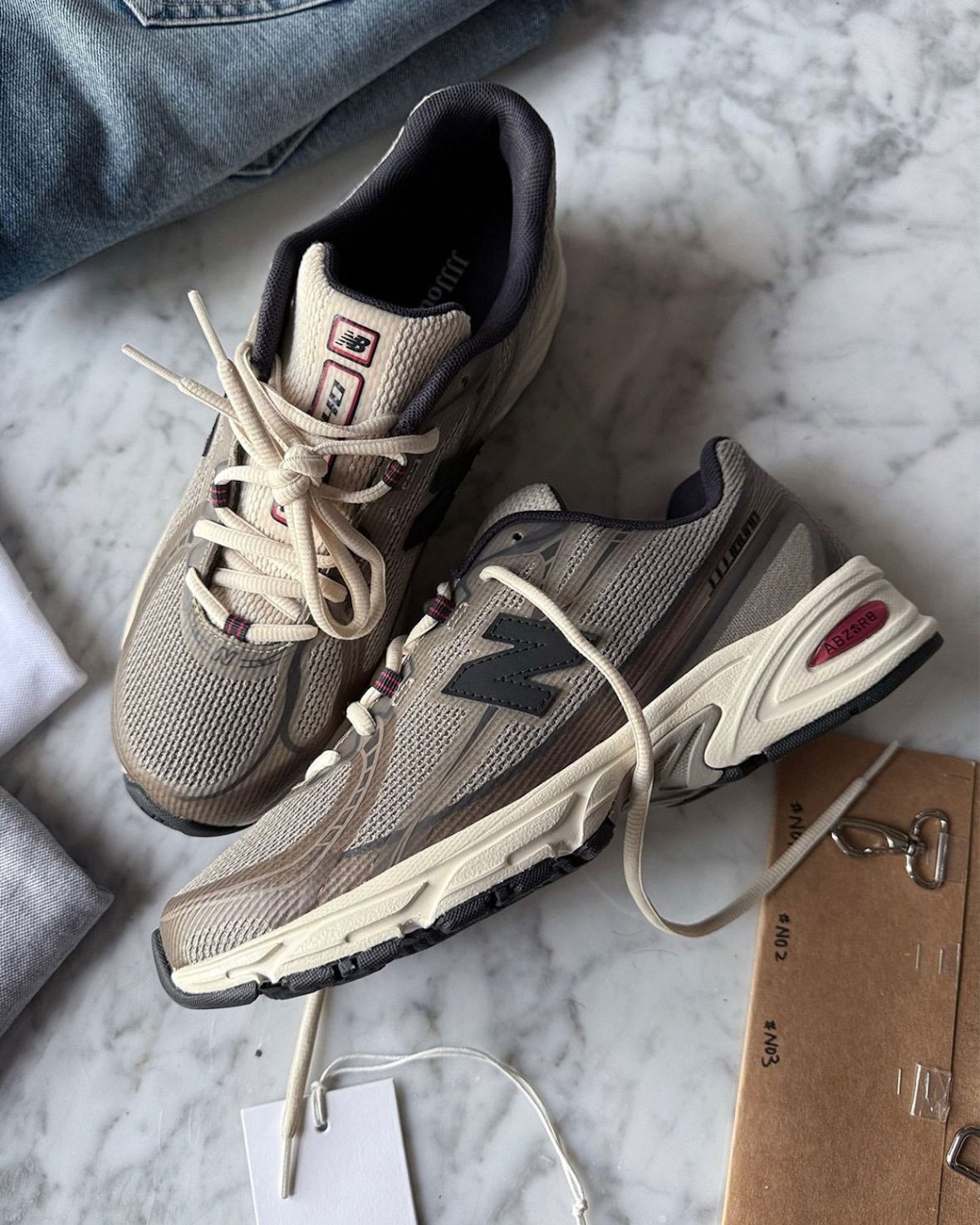 JJJJound x New Balance 740N in Mushroom colorway, featuring no-sew construction with beige, taupe, and off-white upper, navy eyelets, and red accents - detail view 2
