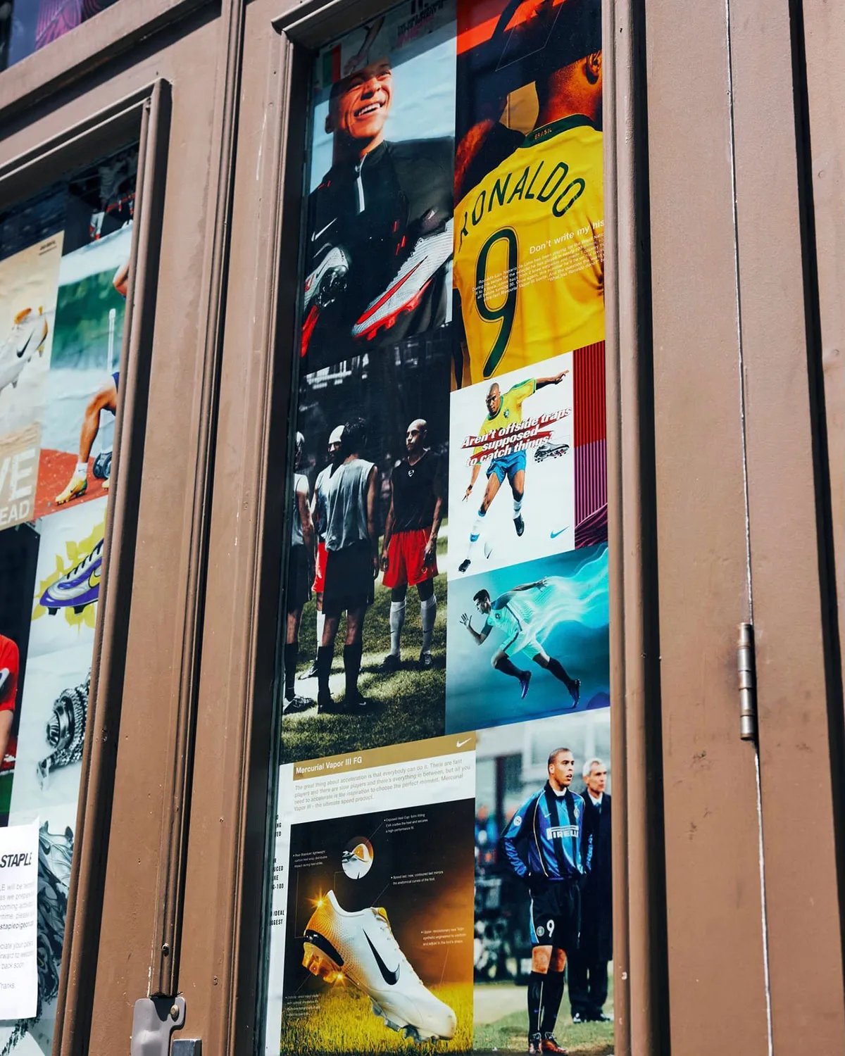 21 Mercer storefront with archival Nike football magazine advertisements and vintage imagery covering windows during World Cup activation - detail view 2