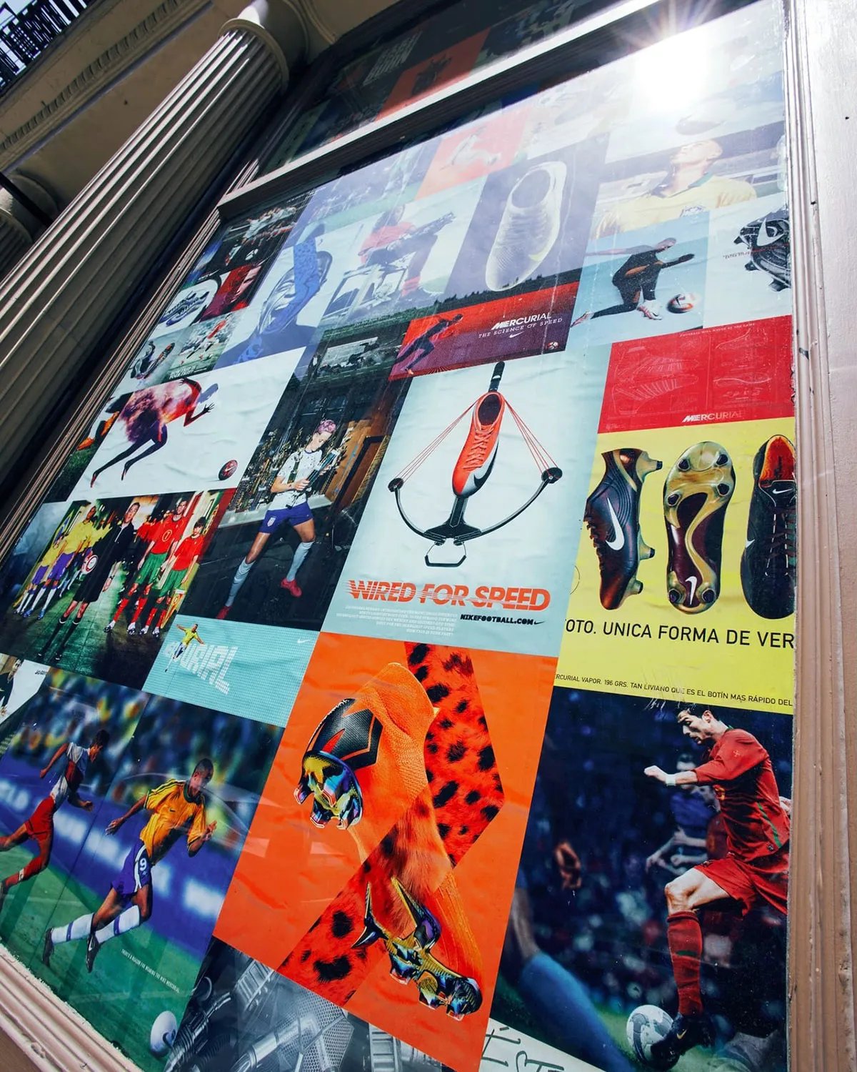 21 Mercer storefront with archival Nike football magazine advertisements and vintage imagery covering windows during World Cup activation - detail view 1