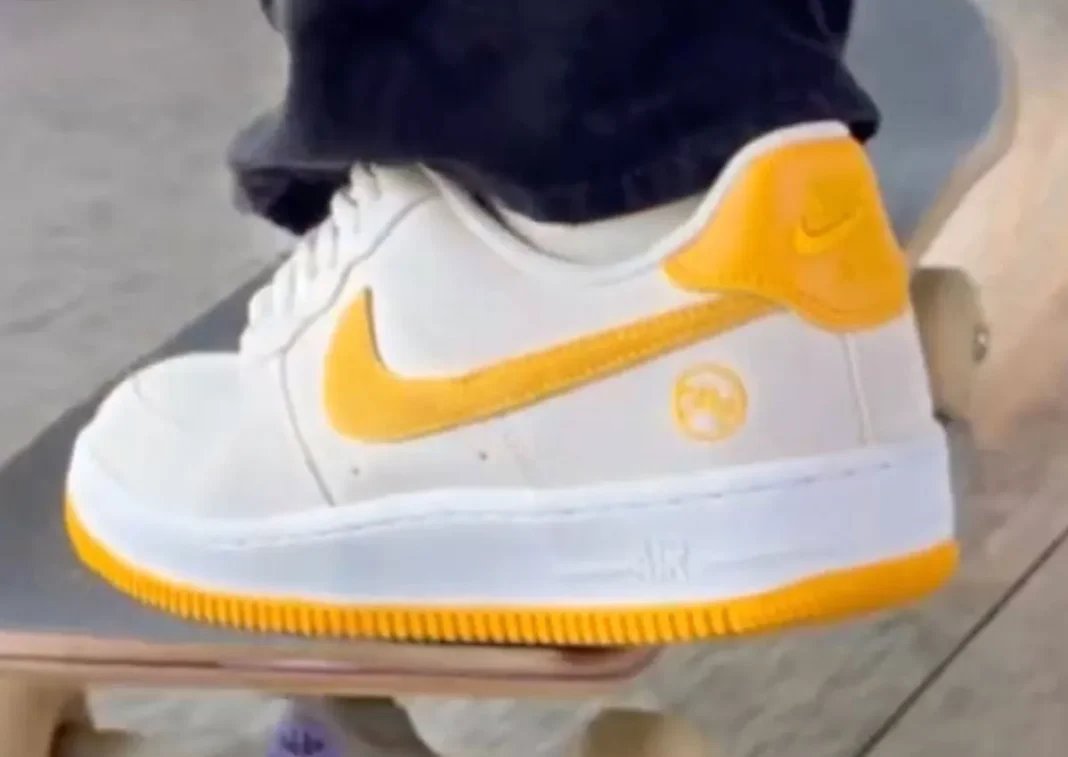 Fly Streetwear x Nike SB Air Force 1 Low in Photon Dust and University Gold colorway, lateral view showing gold suede Swoosh and heel tab - detail view 1