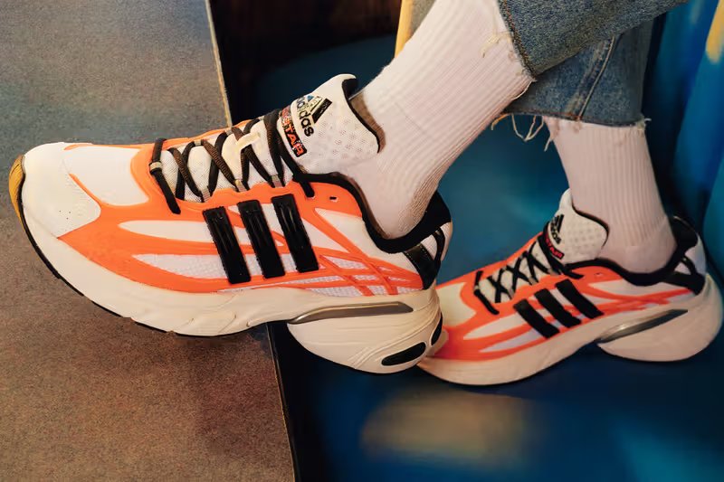 Adidas ADISTAR XLG in Black/Silver and White/Solar Orange colorways with mixed material construction and Y2K-inspired design details - detail view 1