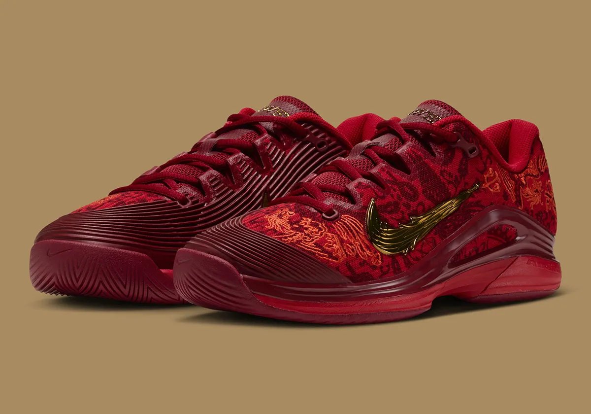 Nike Zoom Vapor 12 PE Qinwen Zheng in red and gold, front three-quarter view showing phoenix hangtag and gold Swoosh