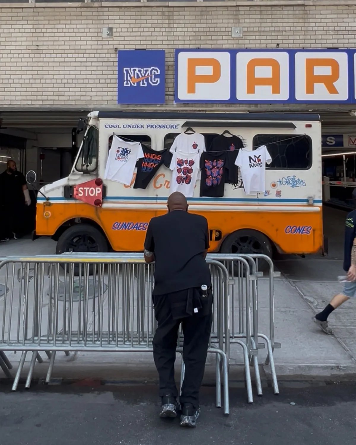 Nike Park N Shop pop-up activation inside Park N Lock garage near Madison Square Garden, featuring custom orange and blue ice cream truck design with vintage Knicks merchandise and hanging Nike Dunks - detail view 4