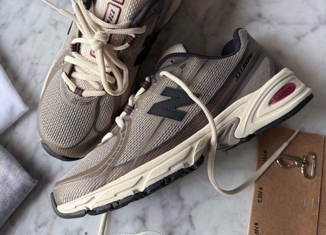 JJJJound x New Balance 740N in Mushroom colorway, featuring no-sew construction with beige, taupe, and off-white upper, navy eyelets, and red accents - detail view 1