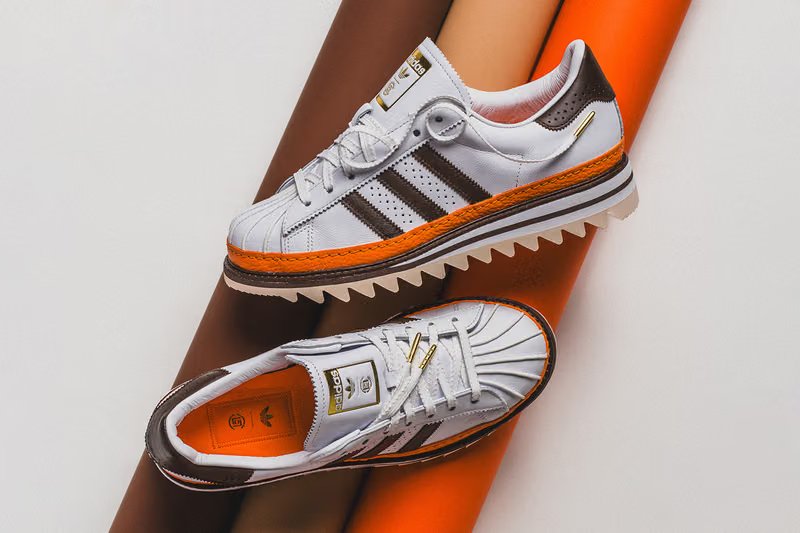 adidas Originals x CLOT Superstar "Unity Orange" sneaker featuring vibrant orange leather upper with white Three Stripes and gold lace tips - detail view 3