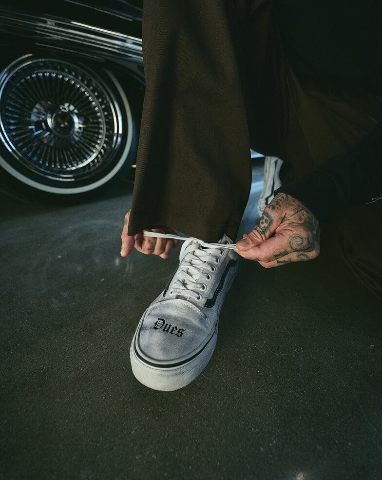 Travis Barker x Vans Old Skool in White and Black colorway, side angle showing classic Old Skool silhouette with collaboration branding - detail view 1