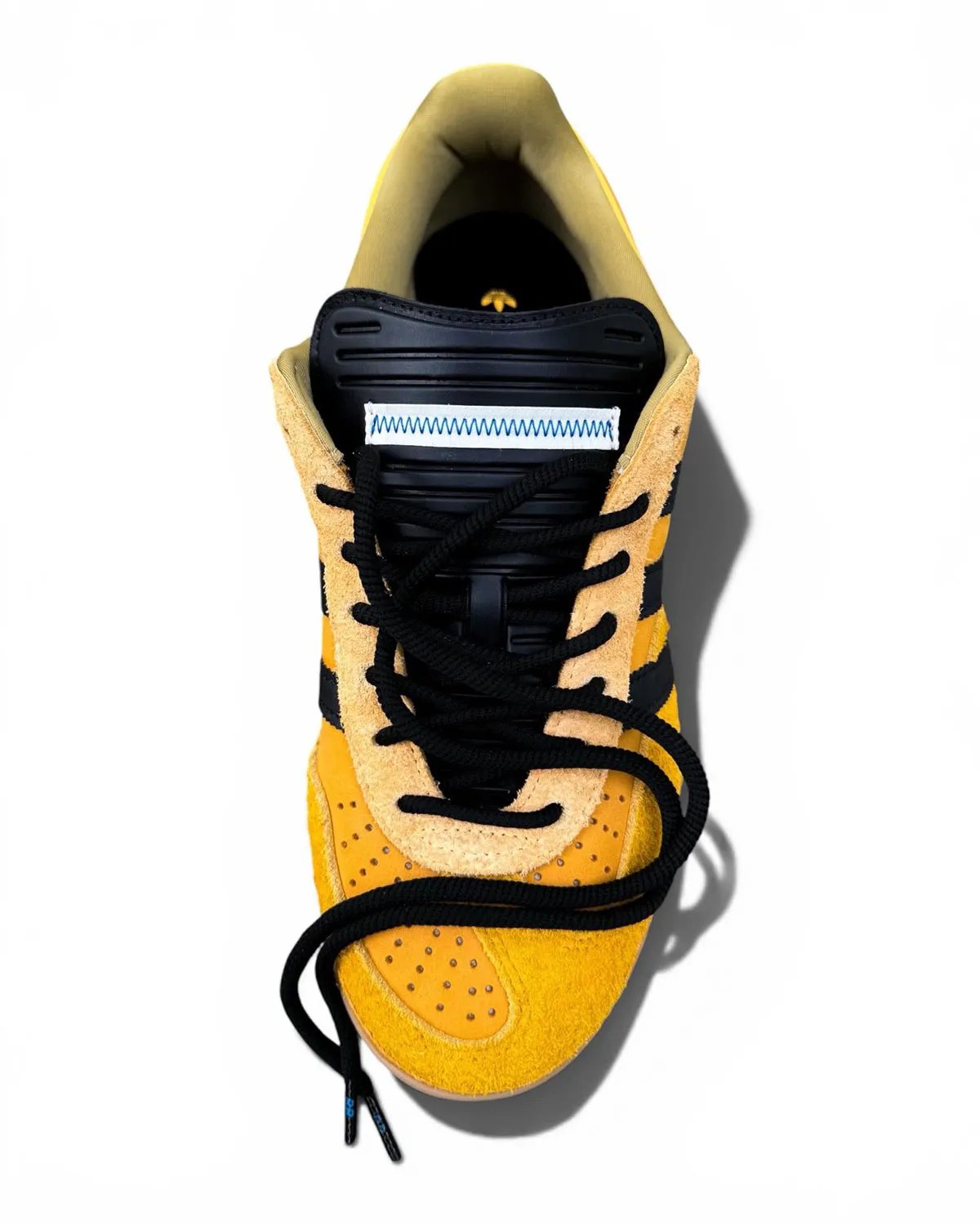 Bad Bunny x adidas Gazelle Indoor in Solar Gold with black stripes, showing canvas foxing and offset T-toe construction - detail view 4
